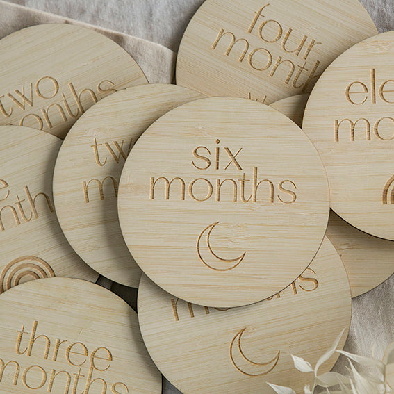 Round bamboo milestone sets. All with the months of the year and different pictures. The one in front says six months and has a crescent moon engraved.