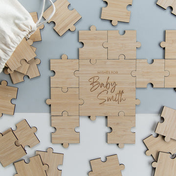 The Personalised Guestbook Jigsaw Puzzle features scattered pieces encircling a center with "Wishes for Baby Smith" in cursive. A fabric bag is included, making it an ideal keepsake for your special event.