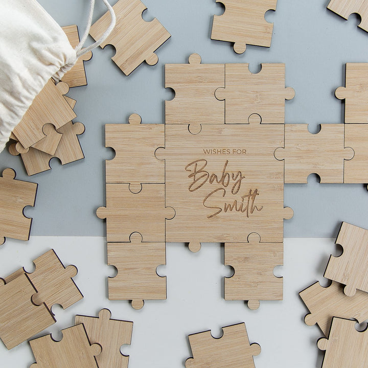 The Personalised Guestbook Jigsaw Puzzle features scattered pieces encircling a center with "Wishes for Baby Smith" in cursive. A fabric bag is included, making it an ideal keepsake for your special event.